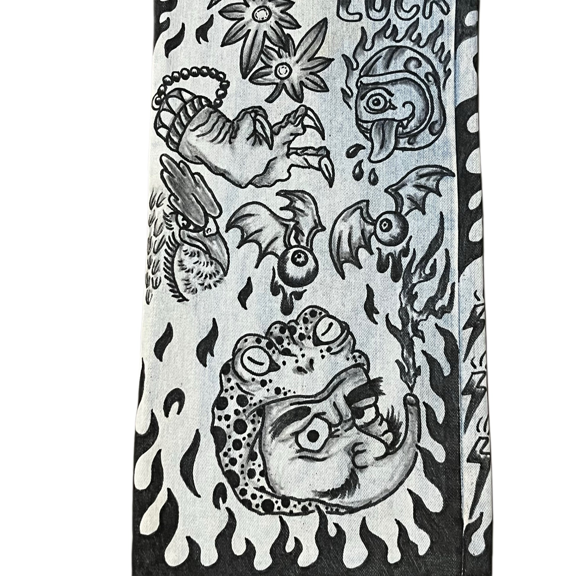 Decorative denim jeans panel with black and white tattoo-style designs on a white background