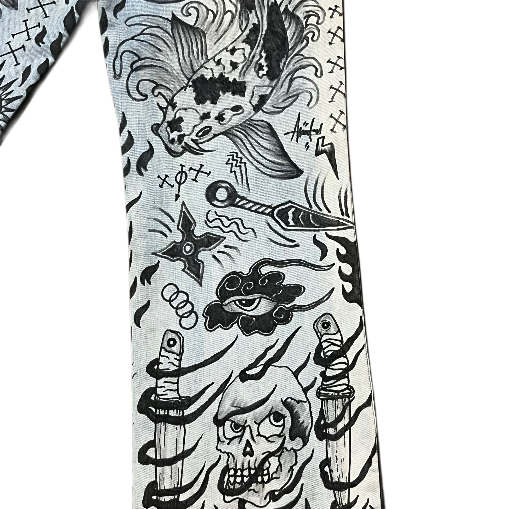 Tattoo design on denim jeans with various elements including fish, skull, and crossed swords.