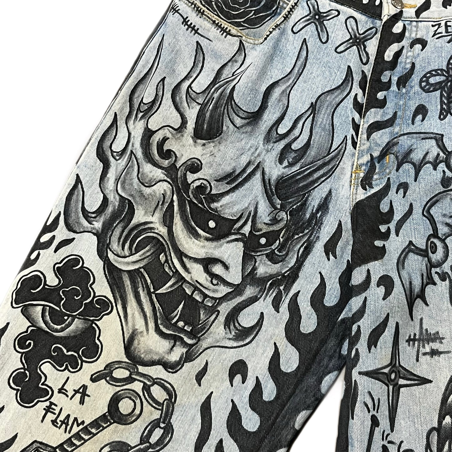 Close-up of a denim jacket with black and white tattoo-style designs.